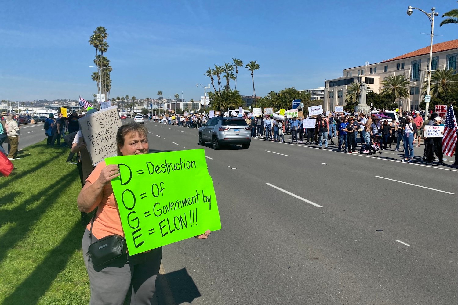 A protester holds a sign about DOGE at a protest on Feb. 17, 2025 in San Diego, California.