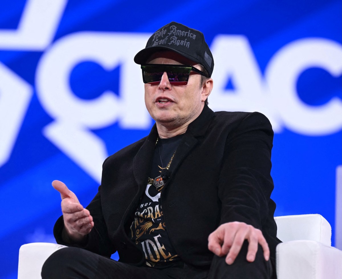 Elon Musk on stage at CPAC in Maryland with sunglasses on and a MAGA hat