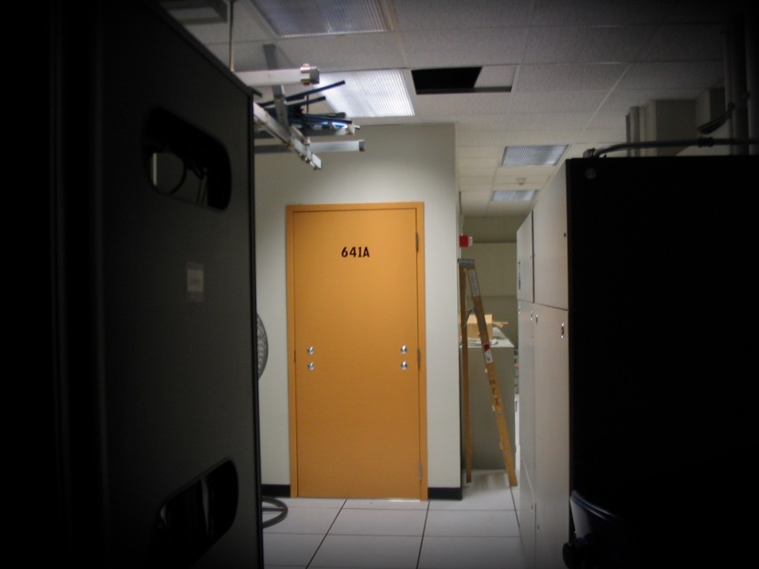 a photo of the exterior of Room 641A, which has a yellow door without a door handle, in a dimly lit datacenter in a San Francisco AT&T hub.