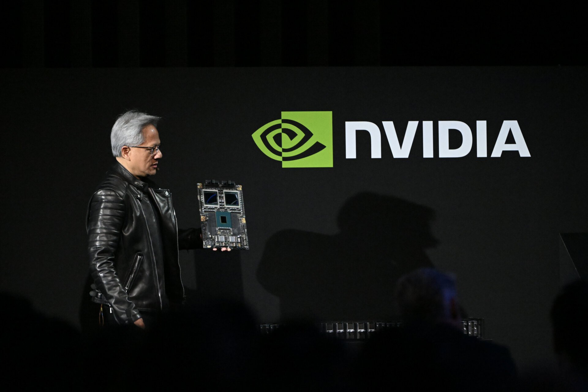 Jensen Huang, co-founder and chief executive officer of Nvidia, holds up the company's AI accelerator chips for data centers