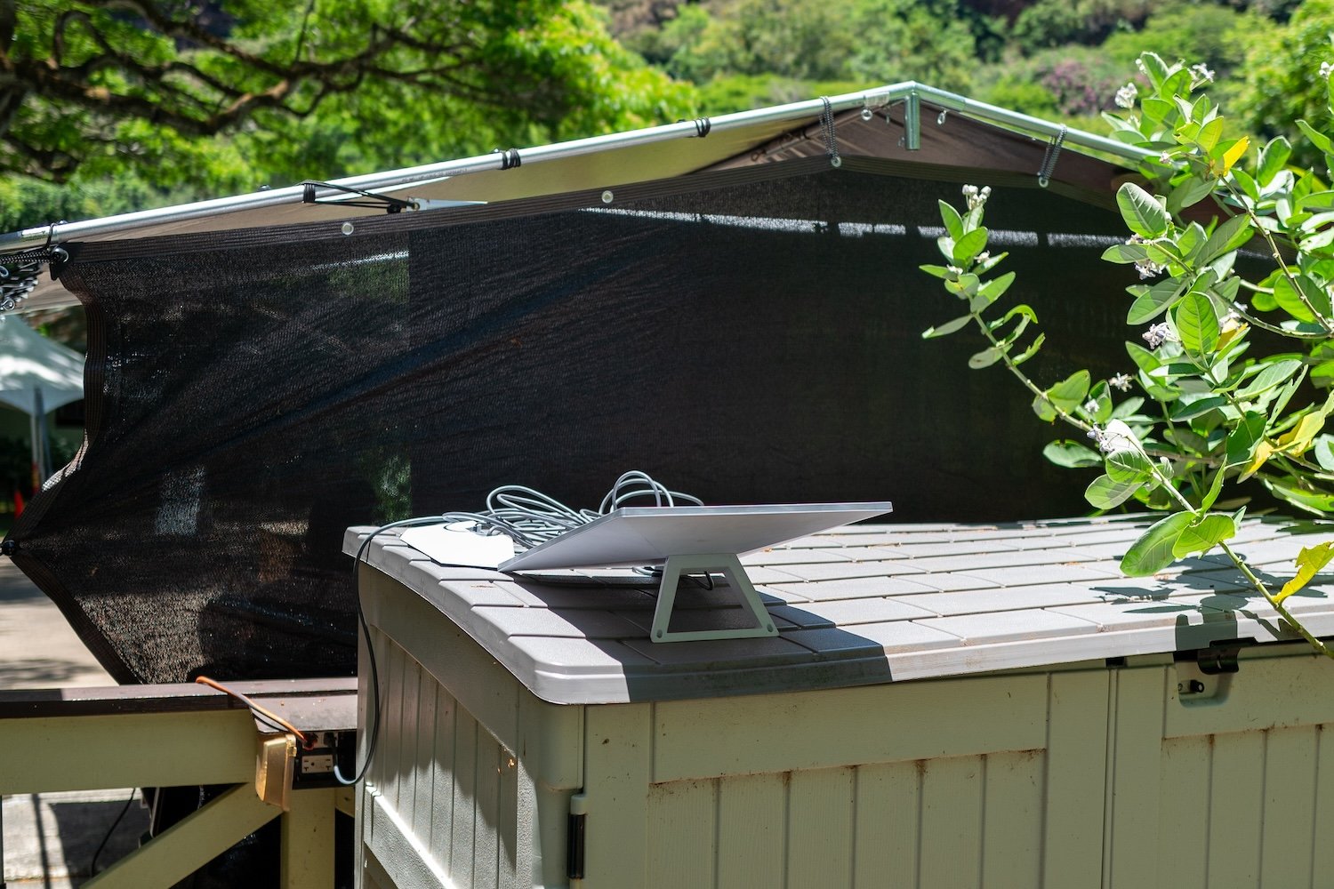 Picture of a Starlink dish mounted on a roof. Wooded area with foliage in the background.
