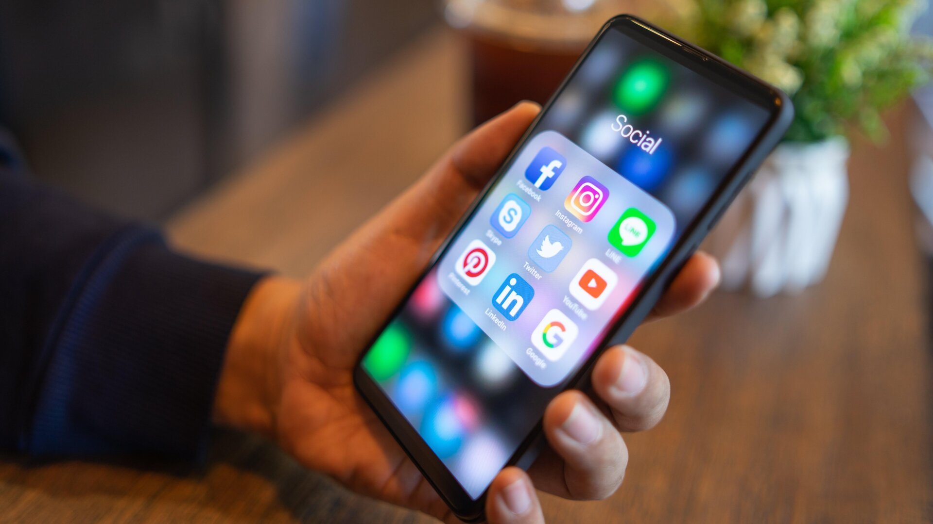 A person holding a cellphone showing social media apps on the homescreen