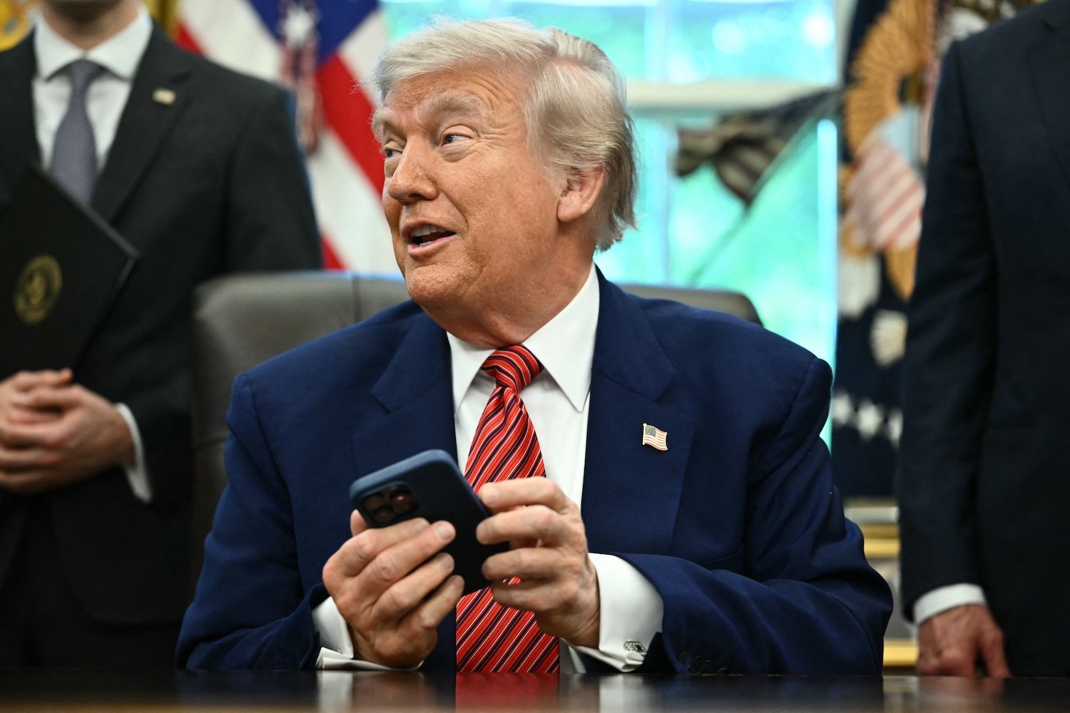 President Donald Trump tries to silence his phone during a press conference in the Oval Office of the White House May 23, 2025 in Washington, DC.